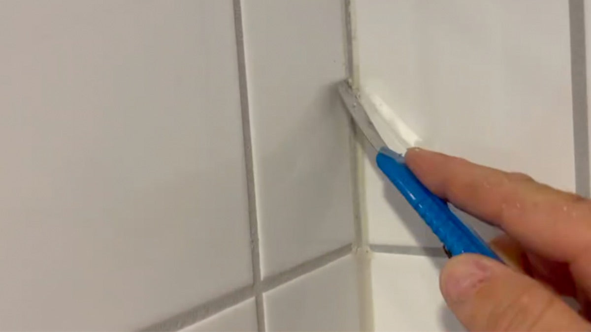 Silikon fjernes fra flisfugene med kniv før mikrosement